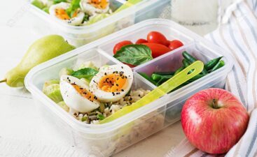 Vegetarian meal prep containers with eggs, brussel sprouts, green beans and tomato. Dinner in lunch box